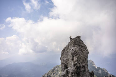 Männlicher Wanderer steht auf dem Gipfel eines Berges gegen den bewölkten Himmel, Europäische Alpen, Lecco, Italien - MCVF00612