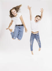 Fröhliche Geschwister springen vor weißem Hintergrund - SDAHF00979