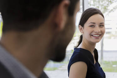 Close-up of smiling businesswoman discussing with male colleague in office - BMOF00445