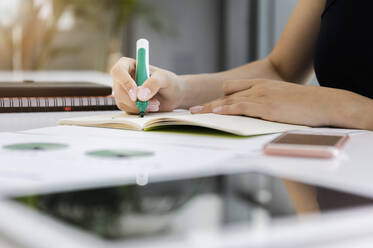 Close-up of businesswoman writing on book at desk in office - BMOF00447