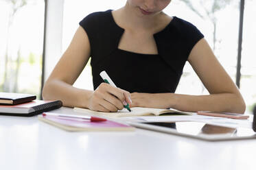 Close-up of fbusinesswoman writing on book at desk in office - BMOF00448
