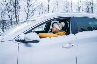 Reife Frau, die über ihr Smartphone spricht, während sie im Winter im Auto sitzt - DGOF01434