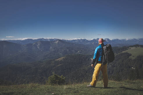 Männlicher Wanderer mit Rucksack und Blick auf die Berge bei klarem Himmel, Otscher, Österreich - HMEF01059