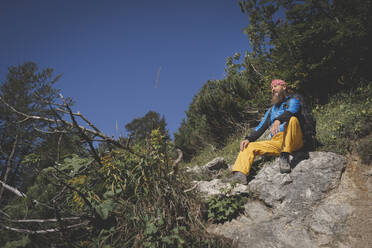 Männlicher Wanderer auf einem Berg sitzend gegen den klaren Himmel an einem sonnigen Tag, Otscher, Österreich - HMEF01064