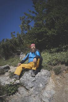 Männlicher Wanderer sitzt an einem sonnigen Tag auf einem Berg, Otscher, Österreich - HMEF01066