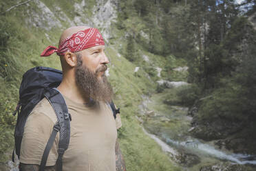 Mature man wearing bandana standing against trees in forest, Otschergraben, Austria - HMEF01070