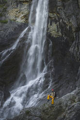 Älterer Mann sitzt auf einem Felsen vor einem Wasserfall, Otscher, Österreich - HMEF01072
