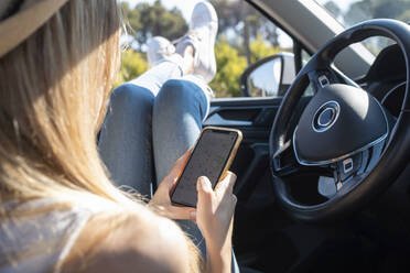 Young woman using mobile phone while sitting in car - JSRF01115