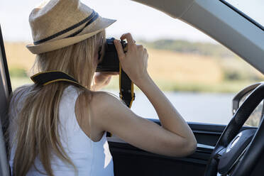 Junge Frau fotografiert durch die Kamera, während sie im Auto sitzt - JSRF01123