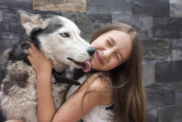 Girl embracing dog while sitting against wall - DSIF00133