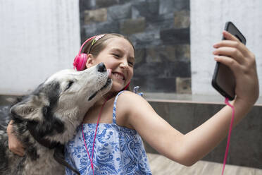 Mädchen nimmt Selfie mit Hund durch Mobiltelefon zu Hause - DSIF00135