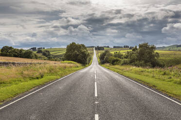 Clouds over empty countryside highway at dawn - WPEF03394