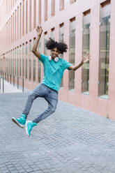 Young man jumping on street in city - XLGF00494
