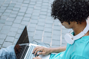 Mann arbeitet am Laptop auf dem Gehweg in der Stadt - XLGF00503