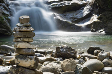 Kleiner Steinhaufen mit plätscherndem Wasserfall im Hintergrund - WGF01354