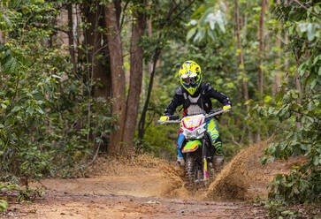 Frau fährt mit ihrem Geländemotorrad auf einem Waldweg in Pak Chong / Thailand - CAVF89252