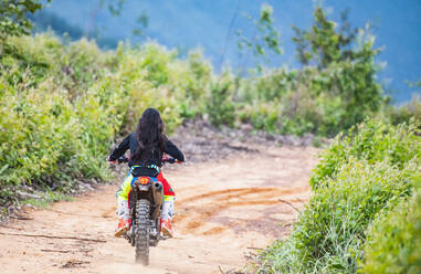 Frau fährt mit ihrem Geländemotorrad auf einem Waldweg in Pak Chong / Thailand - CAVF89253