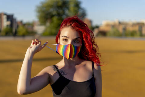 Redhead woman wearing multi colored face mask on sunny day stock photo