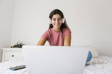 Junge Frau hört Musik, während sie zu Hause am Laptop arbeitet - XLGF00537