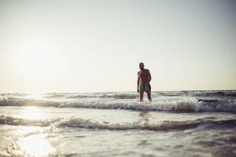 Senior man walking in water at beach stock photo