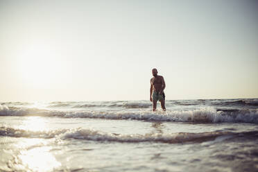 Älterer Mann geht im Wasser am Strand spazieren - MEUF02072