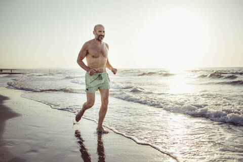 Senior man running at beach stock photo