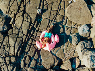 Mann entspannt sich auf Flamingo-Ring am Strand - MEUF02093