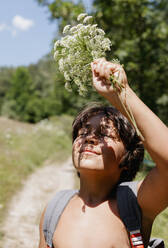 Junge hält Blume beim Wandern auf einem Berg - VABF03471