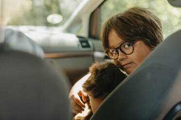 Boy sitting with puppy in car - VABF03487