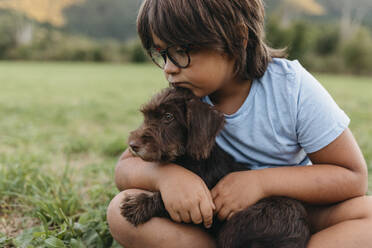 Junge sitzt mit Hund im Gras im Hinterhof - VABF03508