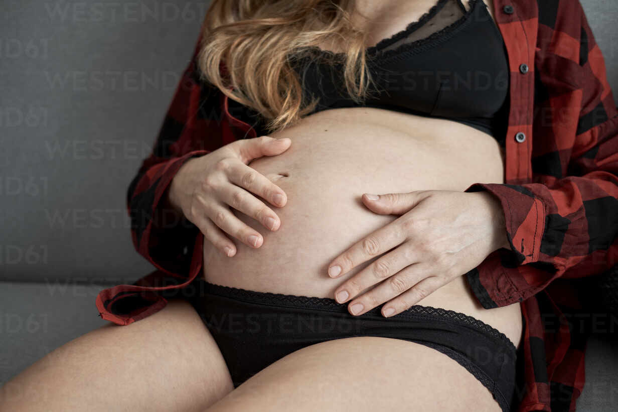 Woman in underwear with her hands on her stomach - Stock Photo
