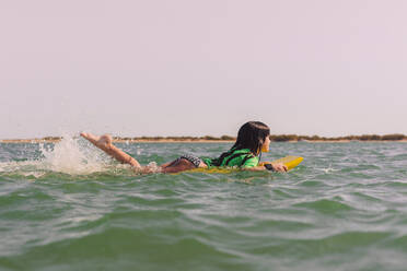 Girl bodyboarding on sea against clear sky during sunset - ERRF04405