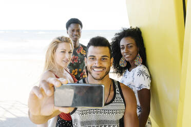 Friends taking selfie while standing in lifeguard hut at beach - RDGF00140