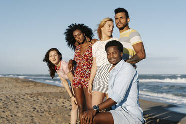 Glückliche junge Freunde stehen am Strand während eines sonnigen Tages - RDGF00157