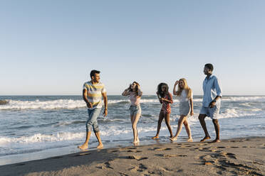 Junge Freunde spazieren am Strand während eines sonnigen Tages - RDGF00165