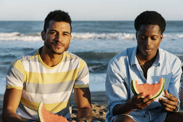 Junge Freunde, die am Strand sitzend Wassermelone essen - RDGF00172