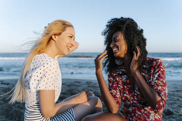 Friends laughing while talking to each other on beach - RDGF00185