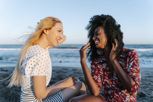 Lachende Freunde, die am Strand miteinander reden - RDGF00185