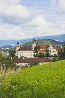 Austria, Carinthia, Sankt Paul im Lavanttal, Springtime meadow with Saint Pauls Abbey in background - AIF00702