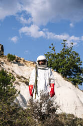 Männlicher Astronaut im Raumanzug auf einem Berg stehend gegen den Himmel - JCMF01436