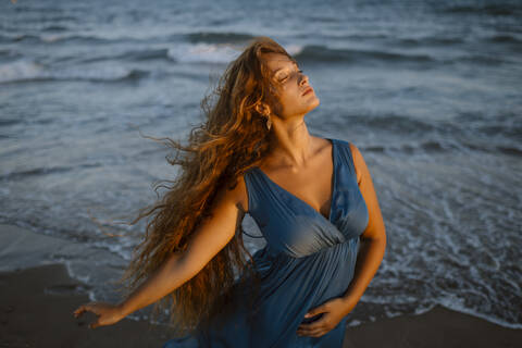 Beautiful woman dancing at beach during sunset stock photo