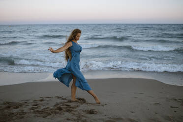 Beautiful woman dancing while standing at beach - GMLF00628