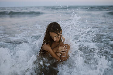 Junge Frau beim Baden im Meer bei Sonnenuntergang - GMLF00635