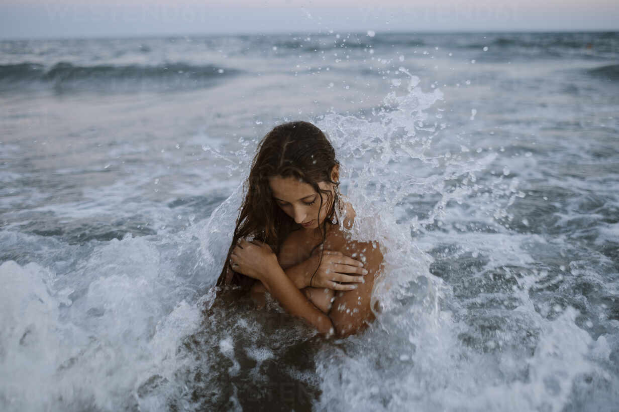 Young woman taking bath in sea during sunset stock photo