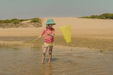 Mädchen fischt Krabben im Meer, während sie gegen den klaren Himmel an einem sonnigen Tag steht - ERRF04416