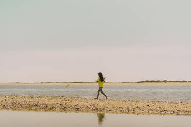 Mädchen läuft am Strand gegen den Himmel an einem sonnigen Tag - ERRF04421
