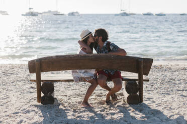 Paar küsst auf einer Bank am Meer sitzend - EGAF00762