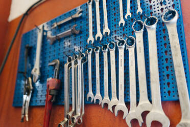 Close-up of work tools hanging on pegboard in workshop - EGAF00777