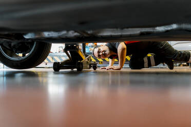 Male mechanic examining car tire in auto repair shop - EGAF00784