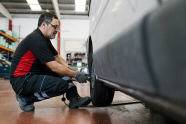 Automechaniker beim Einstellen von Autoreifen in der Werkstatt - EGAF00789